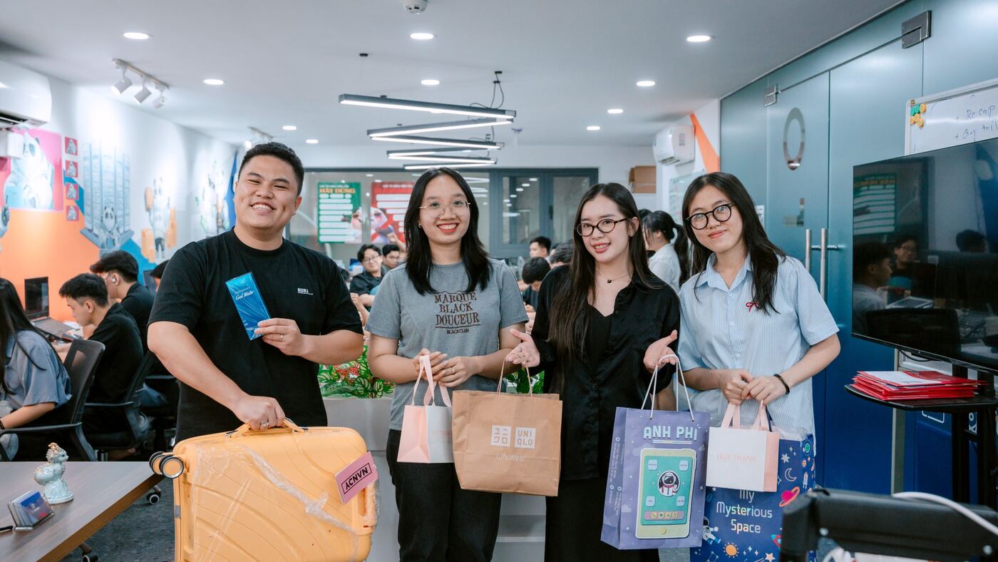 Nhân viên MONA cầm quà vui vẻ chụp ảnh trong không gian văn phòng